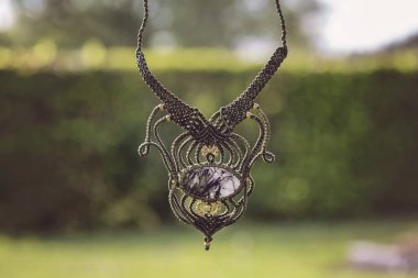 Yeşil açık bokeh arka planda doğal mineral değerli taş ile Boho tarzı makrame kolye