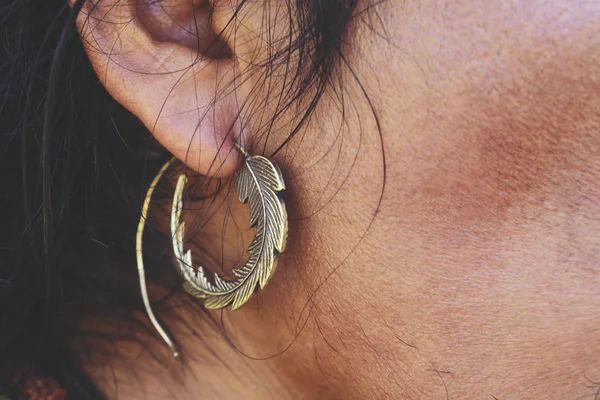 stock image Male ear wearing brass earring in shape of leaf or feather