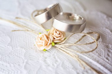 Tatlı yapay küçük gül çiçekleri ile dantel yastık üzerinde Alyans