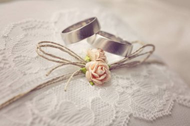 Tatlı yapay küçük gül çiçekleri ile dantel yastık üzerinde Alyans