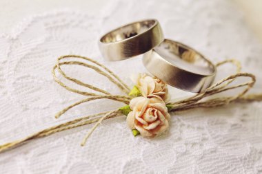 Tatlı yapay küçük gül çiçekleri ile dantel yastık üzerinde Alyans