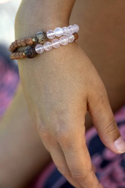Kadın elinde gül kuvars mineral taş boncuk ve rudraksha tohumu yoga bilezik