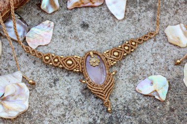 Doğal kayalık ve odunsu arka planda değerli taşlı Macrame kolye