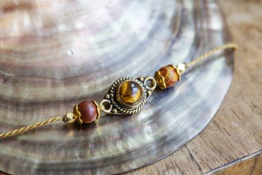 Zarif, küçük bir bilezik, kristal değerli kaplan gözü balmumu iplikte.