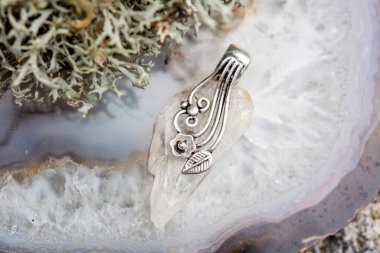 Gri renkli arka planda süslü kristal kuvars gümüş süsleme kolyesi