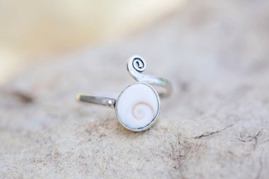 Kabuk beyazı süslemeli beyaz metalden bir yüzük.