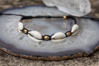 Ağ arka planda beyaz kabuklu makrome boho bileziği