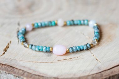 Pembe opal ve yeşil yeşim taşı. Tahta arka planda mineral taşından bilezikler.