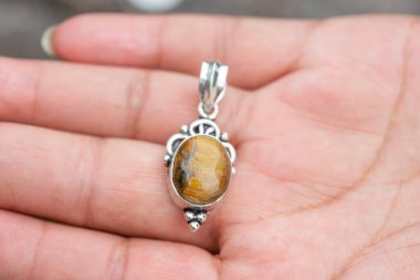 Açık havada, elinizin altında mineral değerli oval kolye görünüyor.