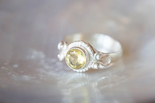 Elegant silver ring with citrine gemstone on rocky background