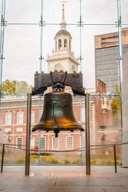 Portrait shot of the liberty bell with Independence Hall in the background clipart
