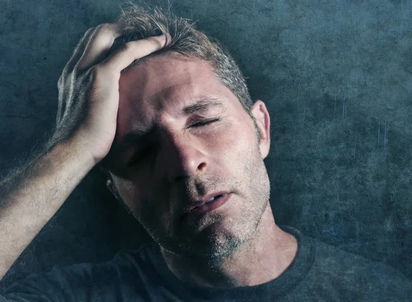 depresyon ve baş ağrısı ile sağlık ve migren kavram açısından endişeli ve hasta üzerinde izole grunge arka planı arıyorum stres tempo kafasında yandan genç çekici ve üzgün adam
