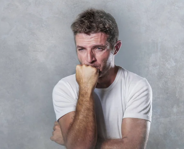 portrait of sad and depressed man biting his fist desperate feeling frustrated and helpless in depression and sadness facial expression concept isolated grunge background