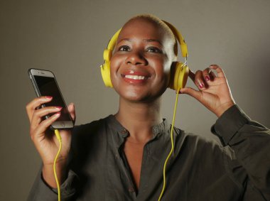 mutlu ve çekici afro Amerikan olan kadın sarı kulaklık ve cep telefonu internet müzik şarkı hipster yaşam tarzı yeşil gri arka plan üzerinde izole neşeli gülümseyen için dinleme