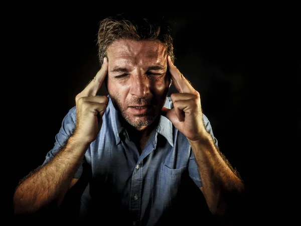 dramatic portrait of attractive sad and depressed man with fingers on his head  desperate suffering depression and headache having problem isolated on black background in sadness and stress