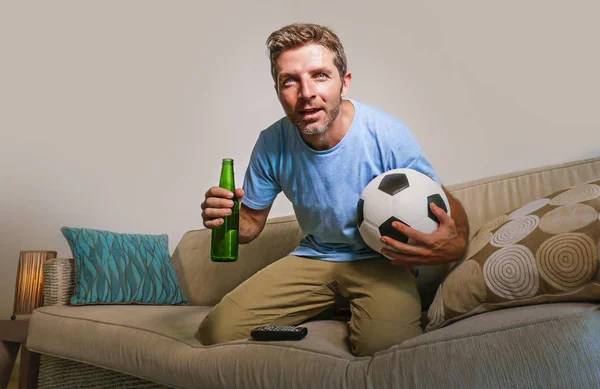 年轻的有吸引力和紧张的人集中看足球比赛在电视举行啤酒瓶和足球在压力下兴奋地享受沙发沙发上的比赛支持者概念 — 图库照片