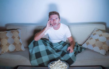 oturma odası koltuk kanepe zevk tamamen konsantre ve baktılar, gece geç saatlerde oturan patlamış mısır yemek televizyon film izlerken genç çekici rahat bir adam portresi yaşam tarzı