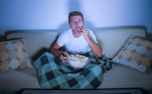 年轻有吸引力的人的生活方式肖像看电影在电视上吃爆米花坐在深夜在客厅沙发沙发上享受充分集中和感兴趣 — 图库照片