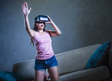 Genç kadın evde 3 boyut merak zevk izlerken video Vr sanal gerçeklik kullanarak oyun oynarken koltuk kanepe gözlükler elleri yanılsama dokunmaya çalışırken eğleniyor