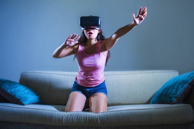 Genç kadın evde 3 boyut merak zevk izlerken video Vr sanal gerçeklik kullanarak oyun oynarken koltuk kanepe gözlükler elleri yanılsama dokunmaya çalışırken eğleniyor