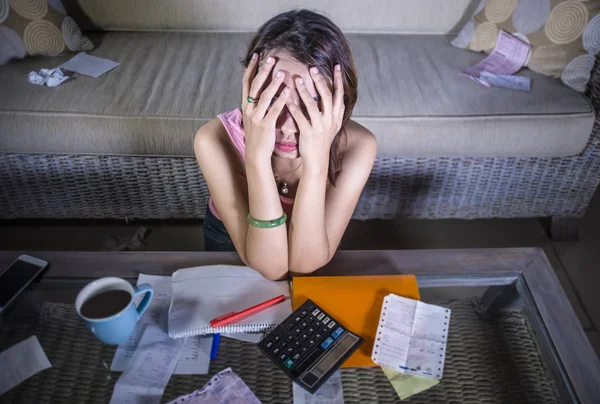 young attractive stressed and worried hispanic woman with calculator and receipts calculating monthly expenses and debt tired and overwhelmed in domestic financial problem and taxes concept