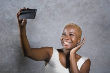 Selfie resim portre ile cep telefonu alarak ya da kendi kendine portre video neşeli poz kaydetme heyecanlı gülümseyen genç güzel ve mutlu siyah afro Amerikalı kadın izole arka plan üzerinde eğleniyor