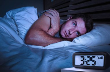 endişeli üzgün genç çekici adam uyanık gözleri kocaman yatak uykusuz yatan bozukluk depresyona ve düşünceli çalar saat ile geç gece saat işaret uyku uykusuzluk acı açıldı