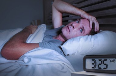 endişeli üzgün genç çekici adam uyanık gözleri kocaman yatak uykusuz yatan bozukluk depresyona ve düşünceli çalar saat ile geç gece saat işaret uyku uykusuzluk acı açıldı