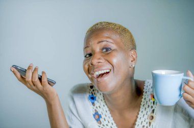 çay ya da kahve fincan neşeli ve iletişim yaşam tarzı heyecan cep telefonu gülümseyen internet sosyal medya app kullanarak tutan izole genç çekici ve mutlu siyah afro Amerikan kadın
