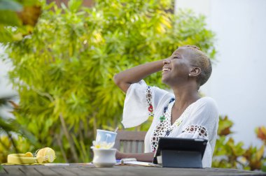 içme çay veya kahve dijital göçebe başarılı yaşam tarzı ve seyahat serbest iş tablet ile açık havada café'de çalışan genç mutlu ve çekici siyah afro Amerikalı kadın rahat