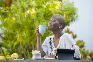 içme çay veya kahve dijital göçebe başarılı yaşam tarzı ve seyahat serbest iş tablet ile açık havada café'de çalışan genç mutlu ve çekici siyah afro Amerikalı kadın rahat