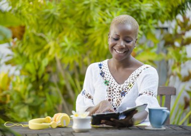 Genç mutlu ve çekici siyah afro Amerikan hipster kadın dijital tablet ile açık havada kafe rahat ve neşeli dijital göçebe başarılı seyahat ve yaşam tarzı blogger serbest iş içinde çalışan.