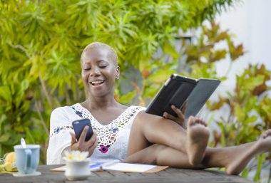 Genç mutlu ve çekici siyah afro Amerikan hipster kadın dijital tablet ile açık havada kafe rahat ve neşeli dijital göçebe başarılı seyahat ve yaşam tarzı blogger serbest iş içinde çalışan.