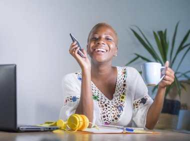 evde cep telefonu dijital göçebe ve serbest meslek işi başarı gülümseyen Internet kullanarak dizüstü bilgisayar ile office çalışan genç mutlu ve çekici siyah afro Amerikan hipster kadın