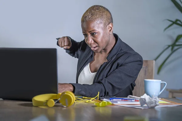 young desperate and stressed african american business woman working  at office desk suffering stress feeling overwhelmed punching upset her laptop computer in work crisis and problem