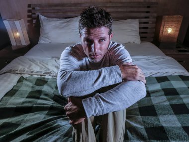 kapalı ev yatak yatak üzgün ve karışık oturan genç umutsuz ve depresif adam portresi acı acı ve depresyon ağlayan kayıp hissi hasta ruh sağlığı ve depresyon