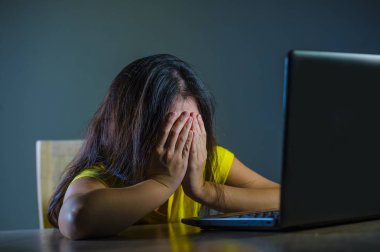 dramatik elleriyle yüzünü kaplayan genç üzgün ve korkmuş kadın portresi vurguladı ve siber zorbalık ve internet sorunu koyu arka plan üzerinde izole dizüstü bilgisayar bakarak endişeli 
