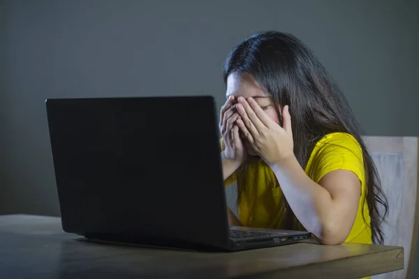 手で顔を覆っている若い悲しい 怖い女性の劇的な肖像画を強調した サイバーいじめ インターネットの問題で暗い背景に分離されたラップトップ コンピューターを見て心配しています — ストック写真
