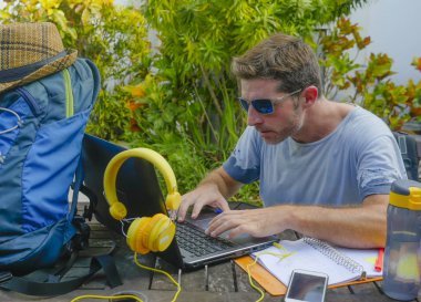 Açık havada dizüstü bilgisayar neşeli ve kendine güvenen çalışan iş çevirmen ve bağımsız iş başarı kavramı uzak ile çalışan genç çekici ve mutlu dijital göçebe erkeğin