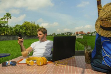 dizüstü bilgisayar ve cep telefonu ile açık havada satırındaki çevirmen ve bağımsız iş Internet serbest çalışma ve girişimci olarak çalışan genç çekici dijital göçebe adam