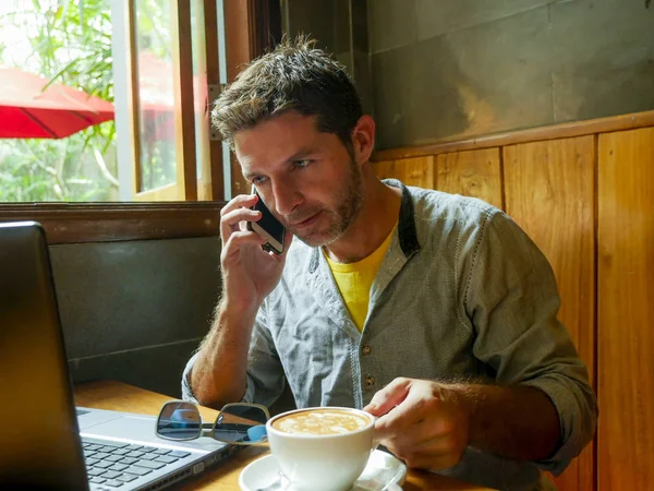 매력적인 성공적인 젊은이 노트북 컴퓨터를 전화에 인터넷 커피가 게에서 일하고 — 스톡 사진