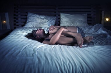 döngüsü ve ağrılı menstruasyon yatakta umutsuz acı mide kramp ağrısı ve adet ağrısı duygu hasta ve hasta yatarken genç çekici Asyalı latin karışık kız dramatik ışık portresi 