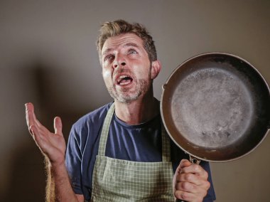 Genç vurguladı ve arka planda stres umutsuz ve hayal kırıklığına uğramış izole iç iş ve dağınık ev kocası çığlık mutfak pan tutan önlük tembel adam boğulmuş 