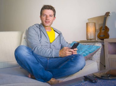 oturma odası kanepe oturan genç güzel çekici ve mutlu adam kanepede internet mobil dating veya hatta flört telefonu kullanarak ağ rahat zevk internet sosyal medya uygulaması