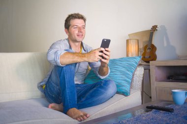 oturma odası kanepe oturan genç güzel çekici ve mutlu adam kanepede internet mobil dating veya hatta flört telefonu kullanarak ağ rahat zevk internet sosyal medya uygulaması