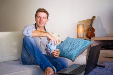 çevirmen ve bağımsız iş iş kavramı mutlu kahve içme dizüstü bilgisayarda ağ kanepede oturan ev oturma odasından çalışan genç çekici ve başarılı erkeğin