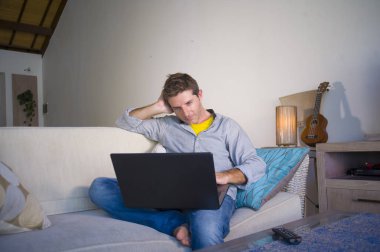 freelancer iş ve bağımsız iş yaşam tarzı kavramı mutlu dizüstü bilgisayarda ağ kanepede oturan ev oturma odasından çalışan genç çekici ve başarılı erkeğin