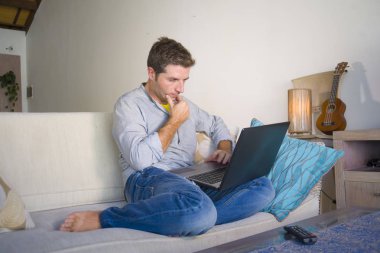 freelancer iş ve bağımsız iş yaşam tarzı kavramı mutlu dizüstü bilgisayarda ağ kanepede oturan ev oturma odasından çalışan genç çekici ve başarılı erkeğin