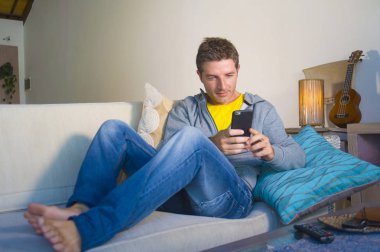oturma odası kanepe oturan genç güzel çekici ve mutlu adam kanepede internet mobil dating veya hatta flört telefonu kullanarak ağ rahat zevk internet sosyal medya uygulaması