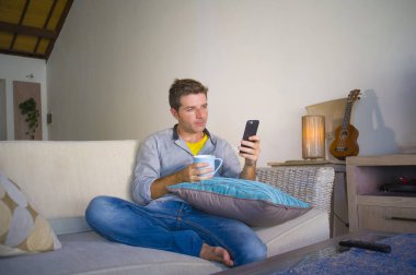 oturma odası kanepe oturan genç güzel çekici ve mutlu adam kanepede internet mobil dating veya hatta flört telefonu kullanarak ağ rahat zevk internet sosyal medya uygulaması